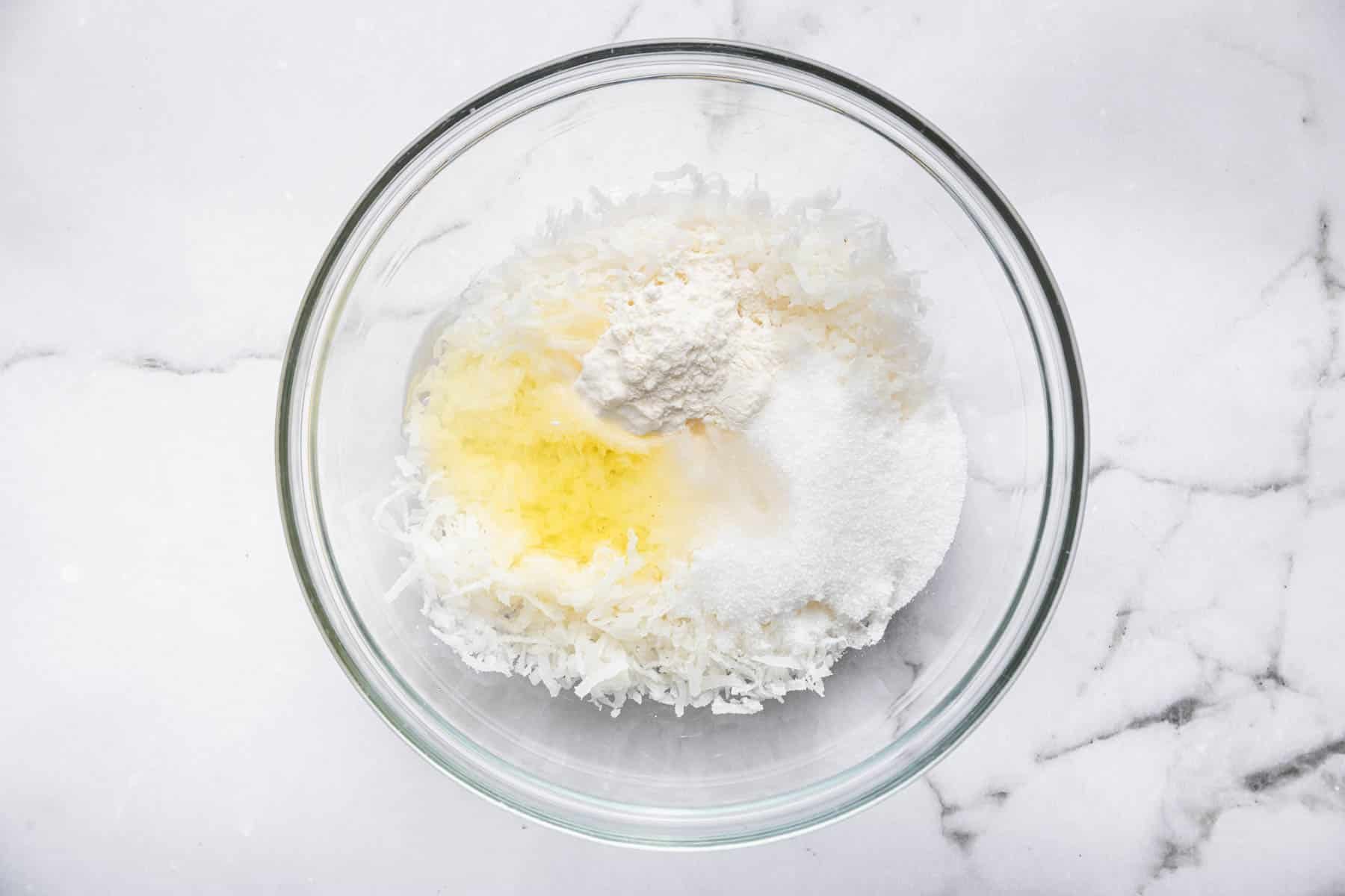 Clear bowl with egg white, flour, sugar, and almond extract.