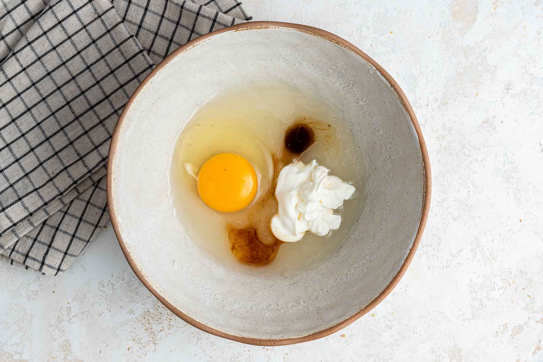 Batter with oil, egg, heavy cream and vanilla in bowl.