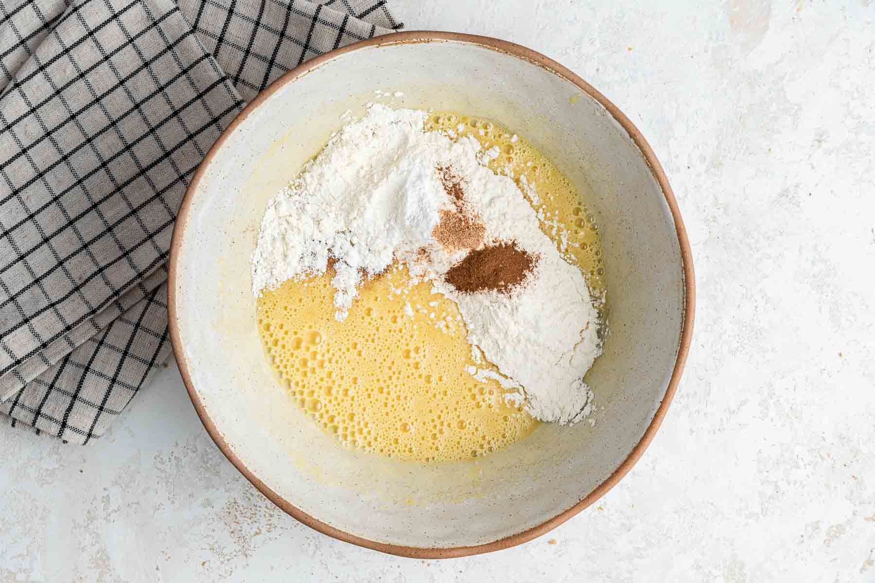 Adding dry ingredients to bowl with yellow batter.
