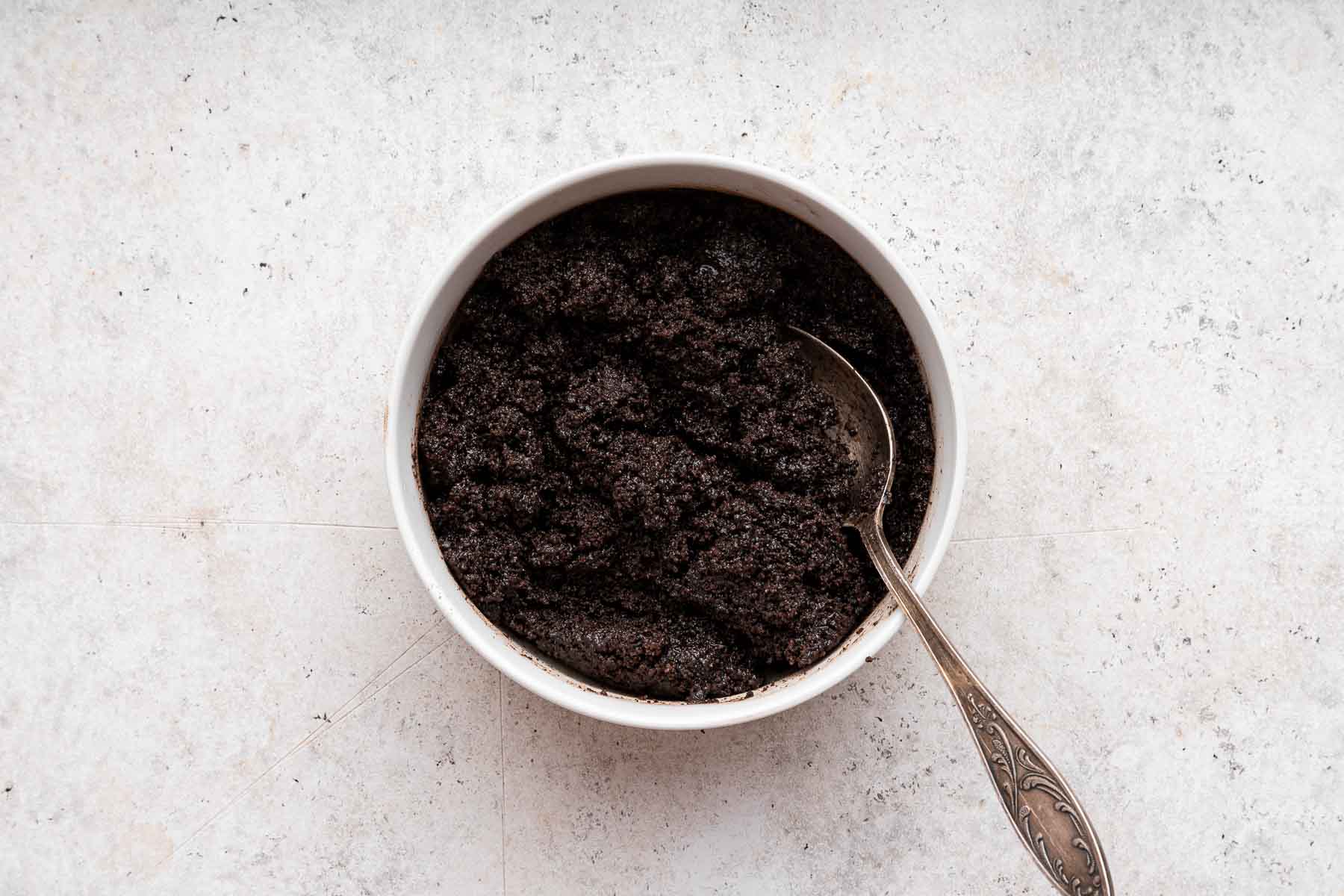 White bowl of crushed oreo crumbs.