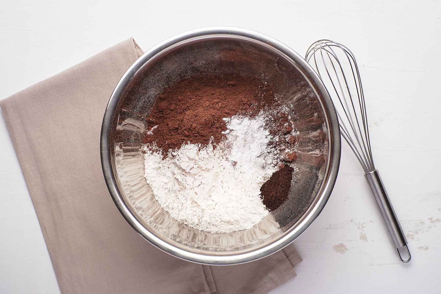 Dry ingredients for cupcakes in silver bowl with whisk.