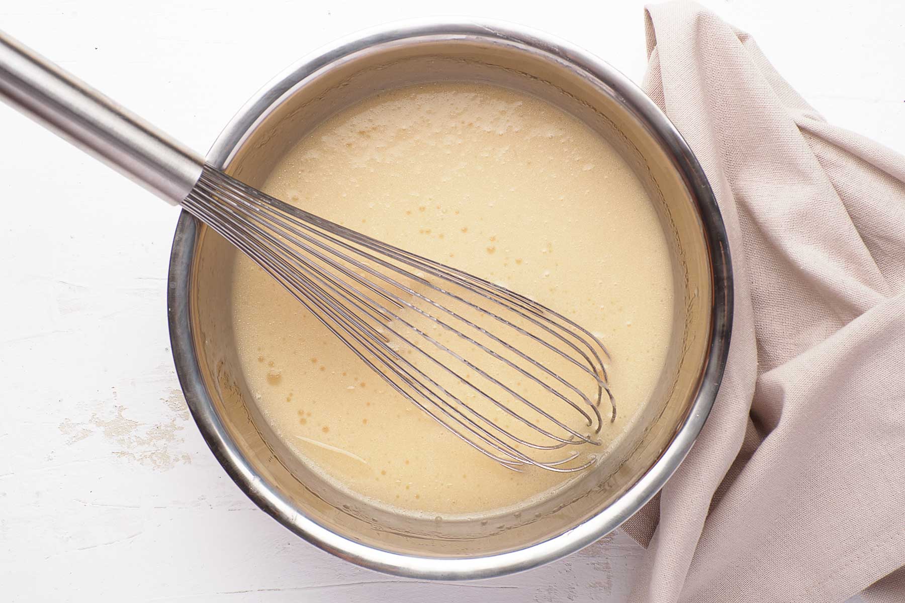 Wet ingredients for cupcakes: milk and oil whisked in a bowl.
