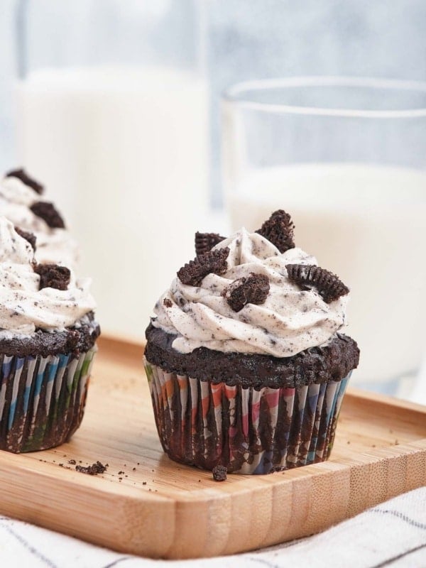 Chocolate cupcakes on wooden board with Oreo frosting and broken cookies on top.