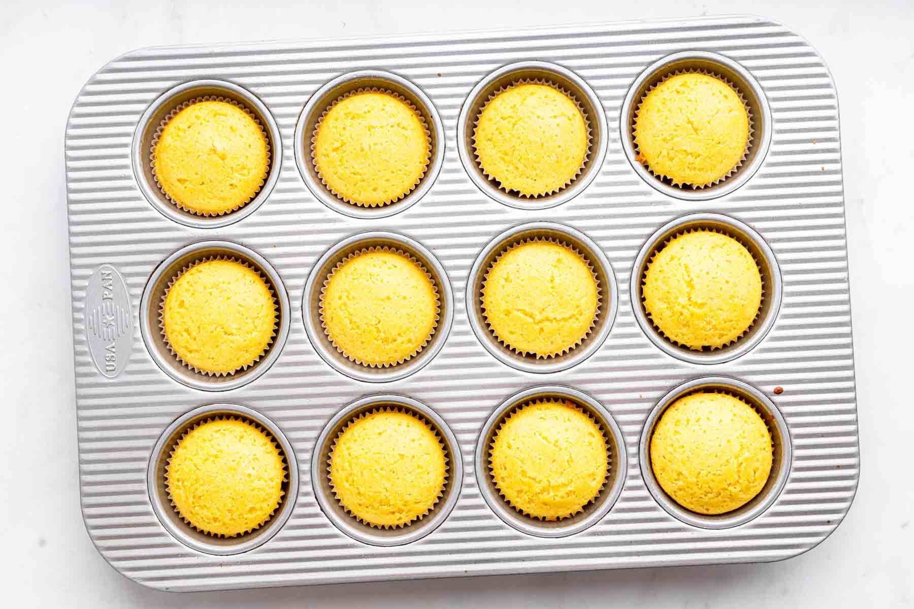 Twelve yellow baked goods in a pan.