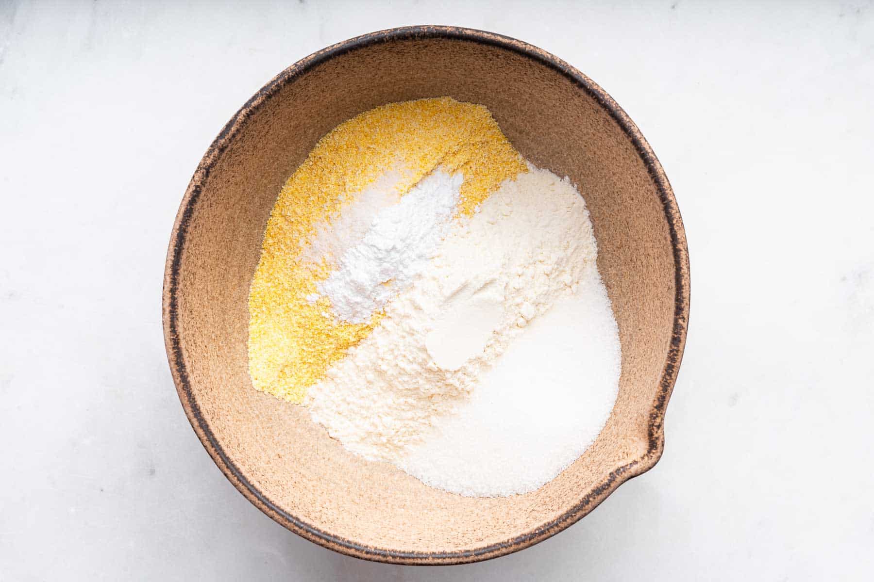 Brown bowl with yellow flour and white flours.