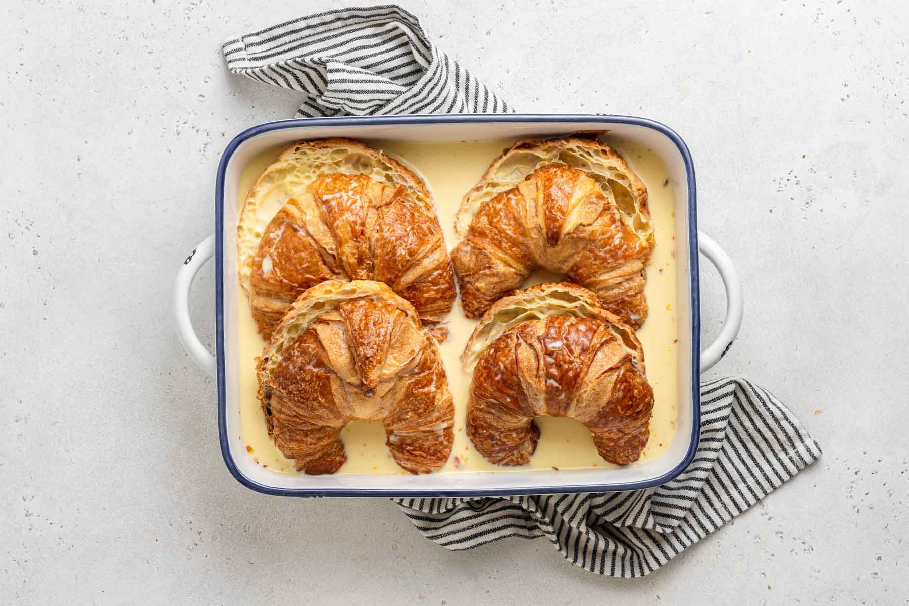 Croissants being soaked in French toast custard mixture.