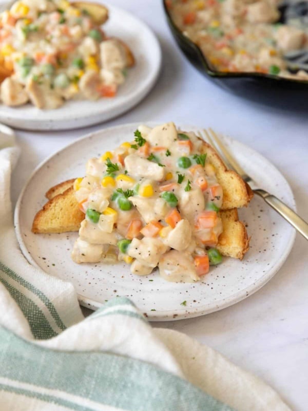 Two plates of chicken pot pie filling over toast.