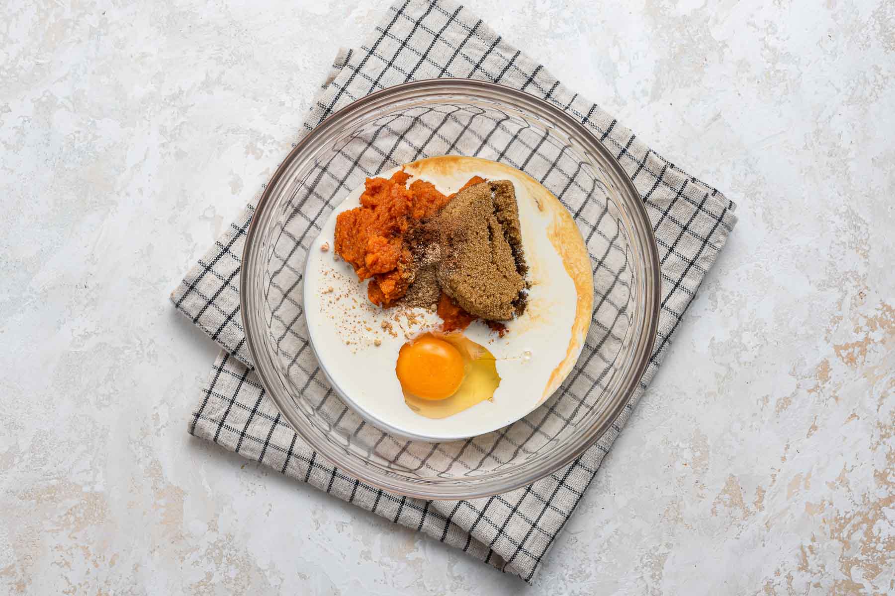 Ingredients for pumpkin pie in clear glass bowl.