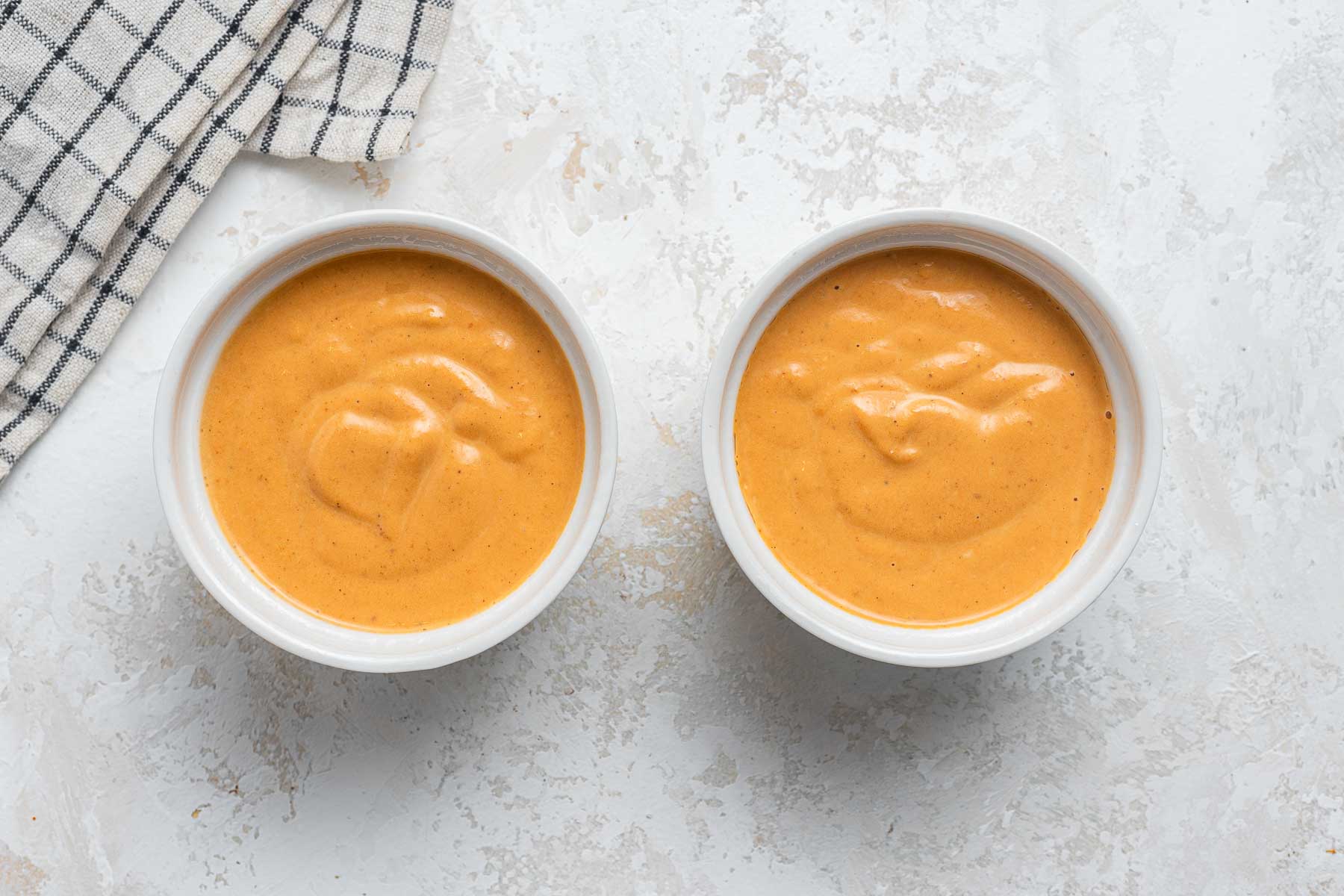 Raw pumpkin pie filling in ramekins.