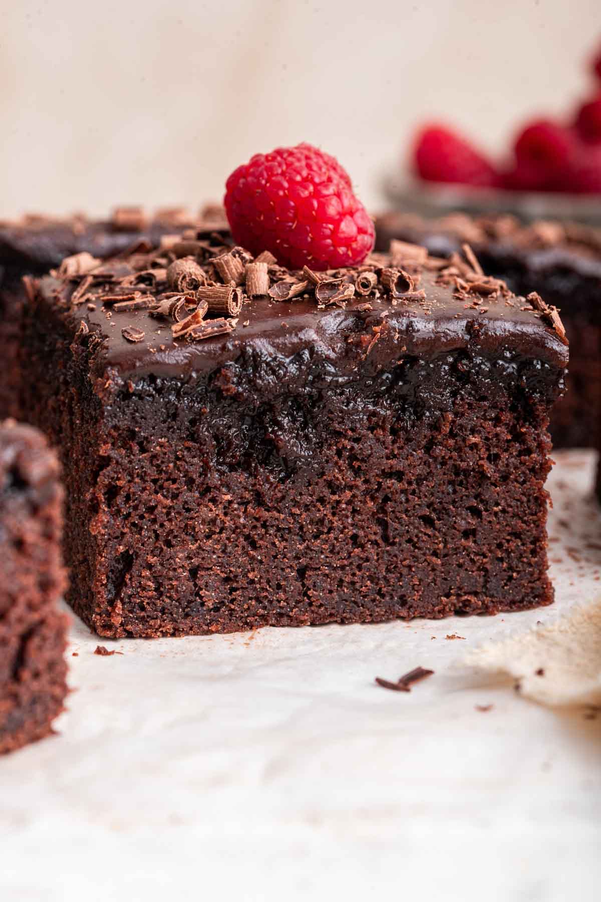 Up close macro shot of chocolate cake with a raspberry on top.