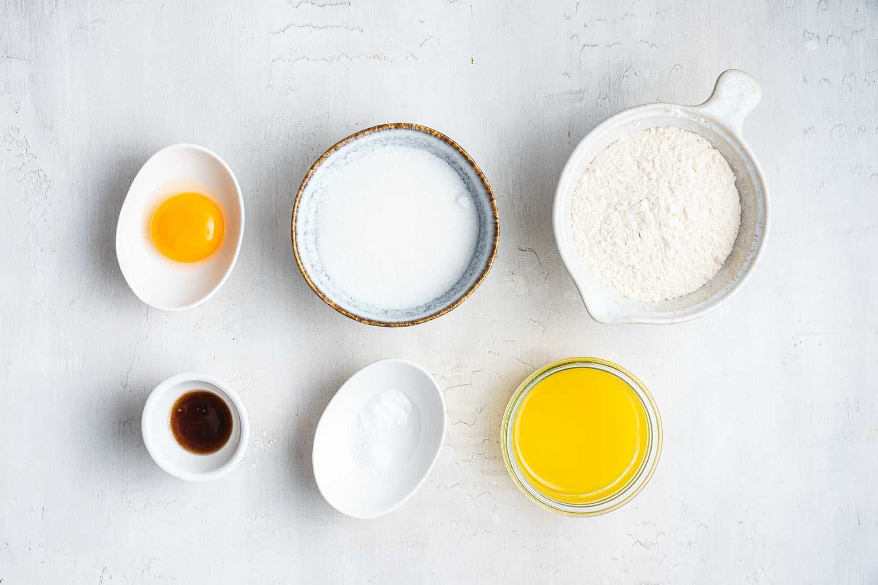 Six small bowls with baking ingredients in each one.