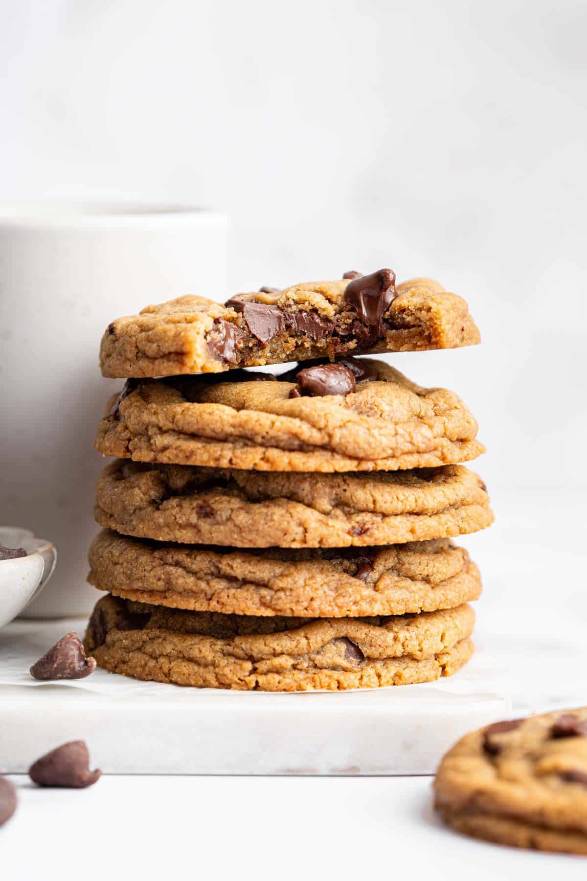 Stack of chocolate chip cookies without eggs with one bite missing.