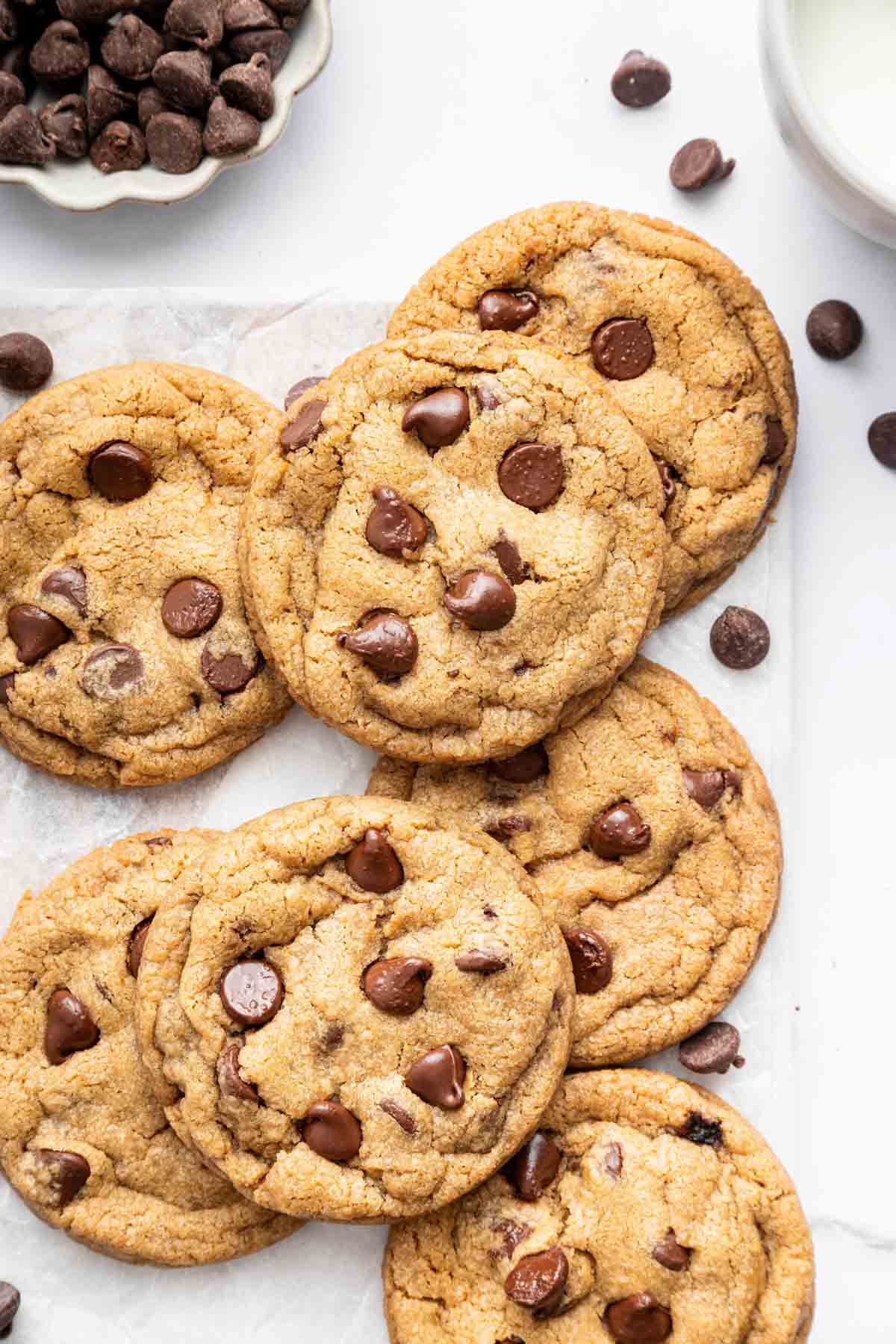 Chocolate chip cookies without eggs on a kitchen counter with extra chocolate chips.
