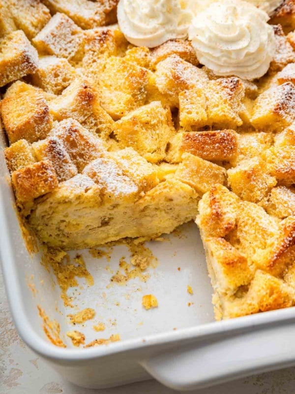 Dish of eggnog bread pudding with one square slice missing.