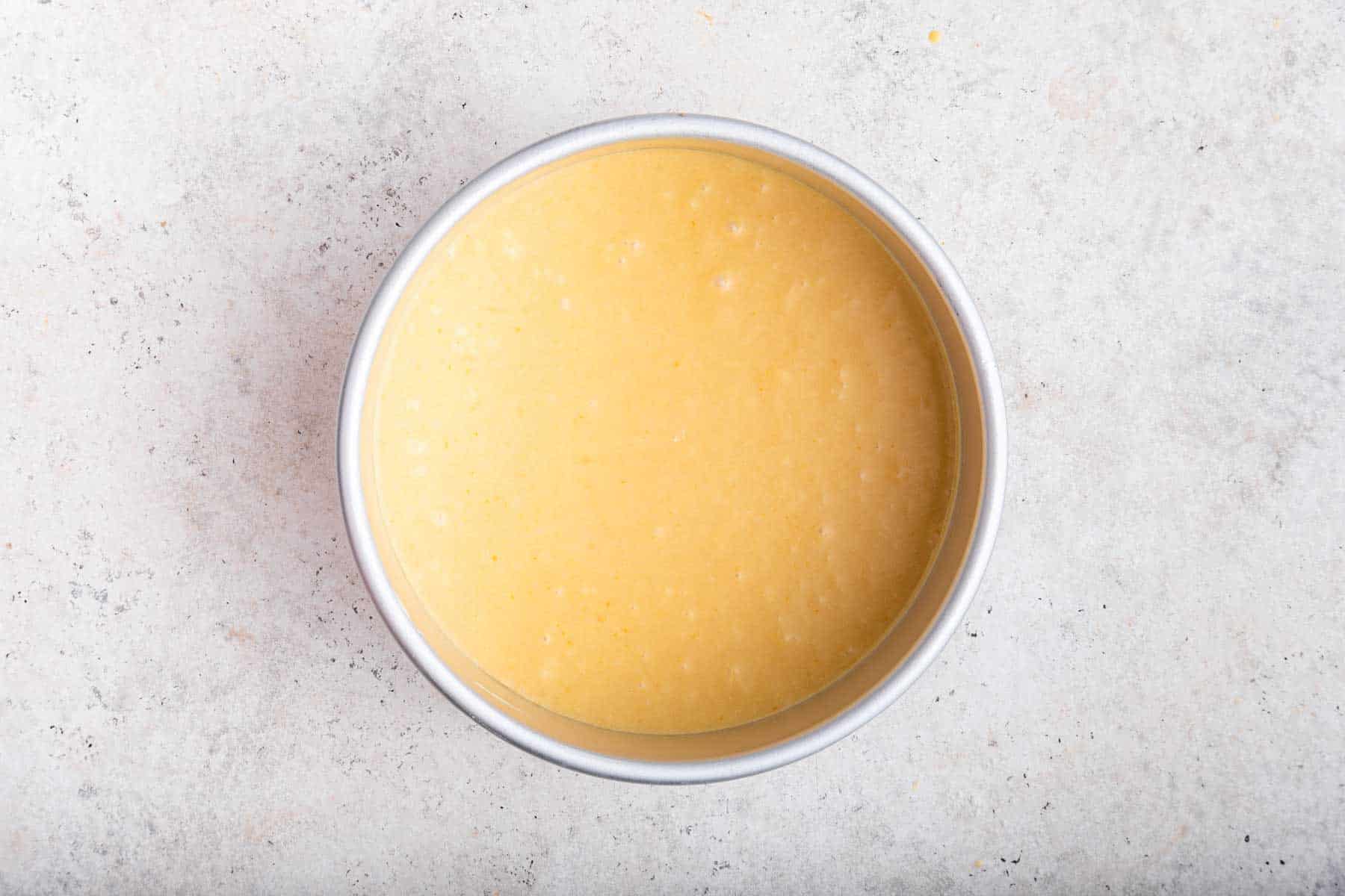 Yellow cake batter in round 6 inch cake pan.
