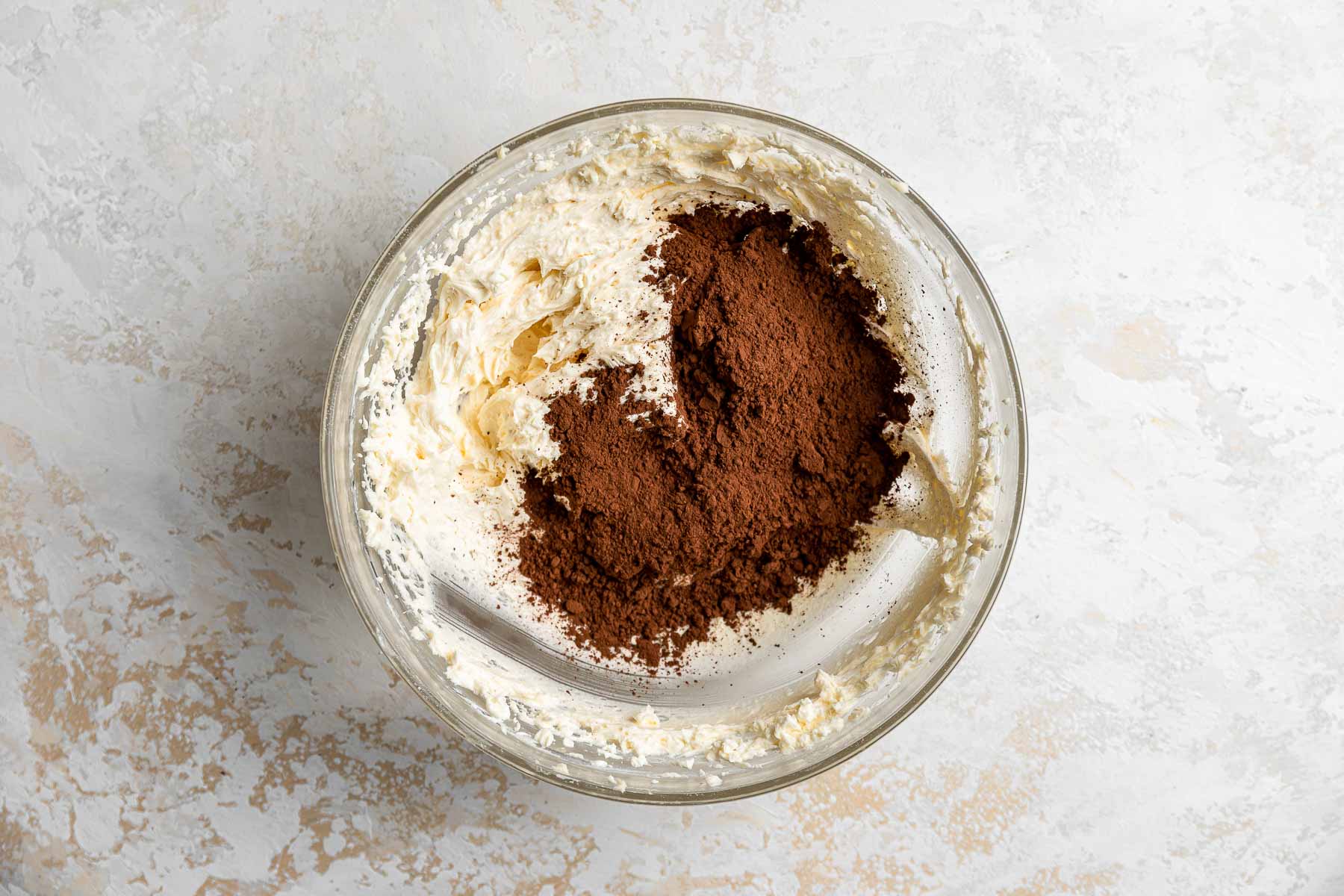 Adding cocoa powder to vanilla buttercream frosting.