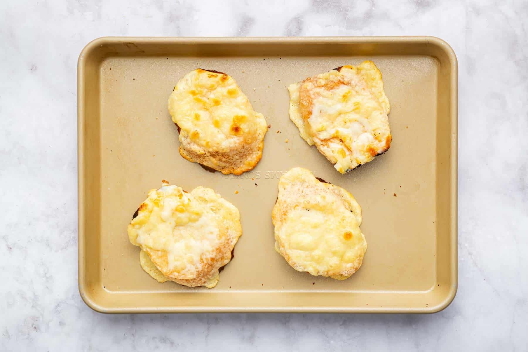 Four slices of bread with melted white cheese on top.