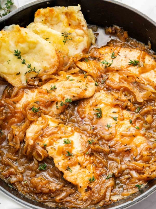 Macro image of French onion chicken recipe in skillet with bread on side.