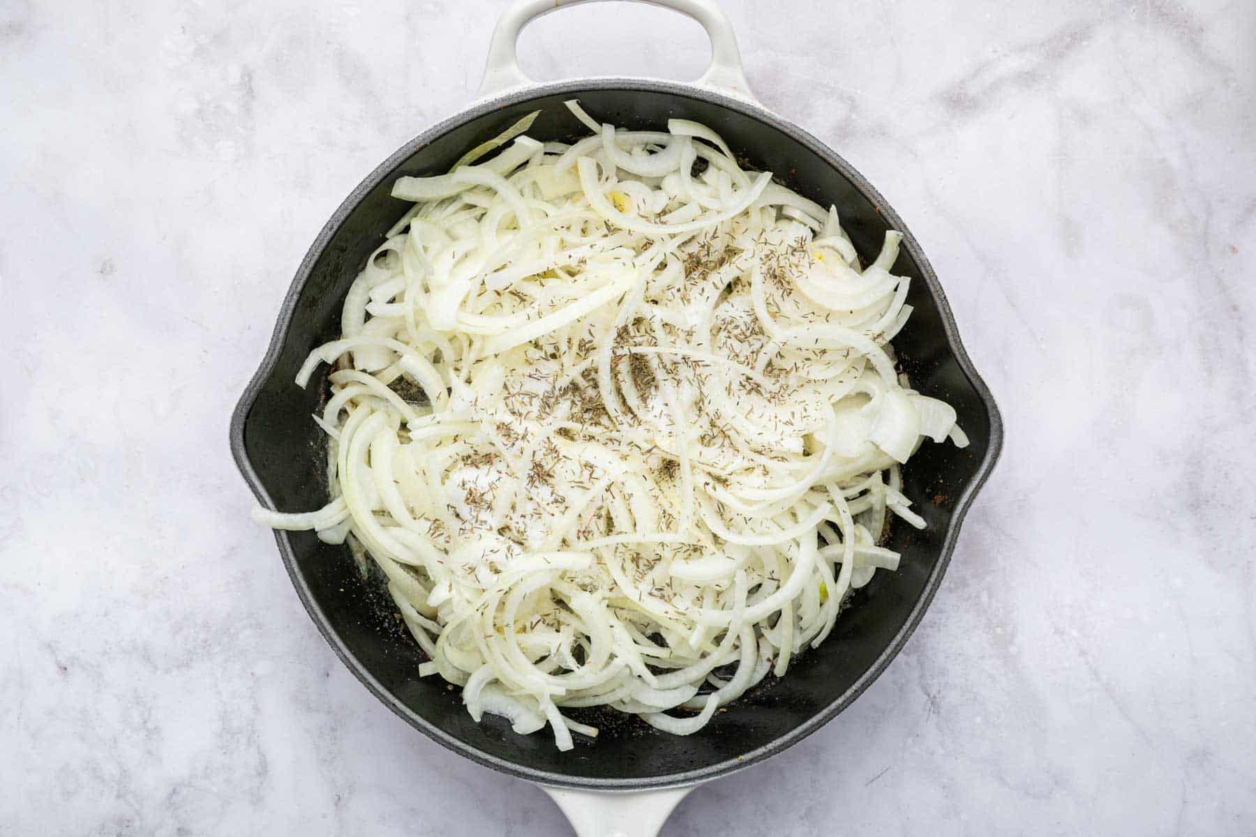 Thinly sliced onion in a cast iron skillet cooking.