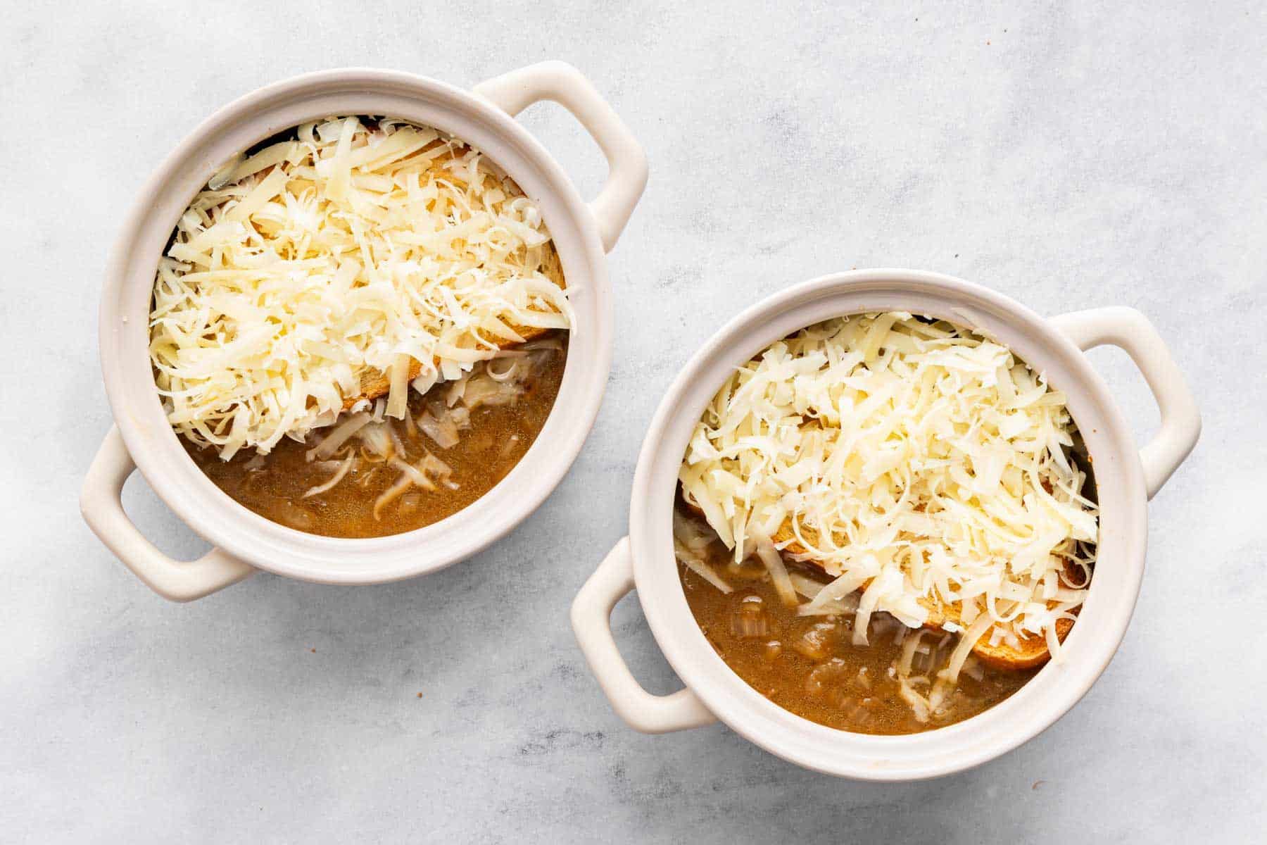 Two bowls of soup with grated white cheese on top.