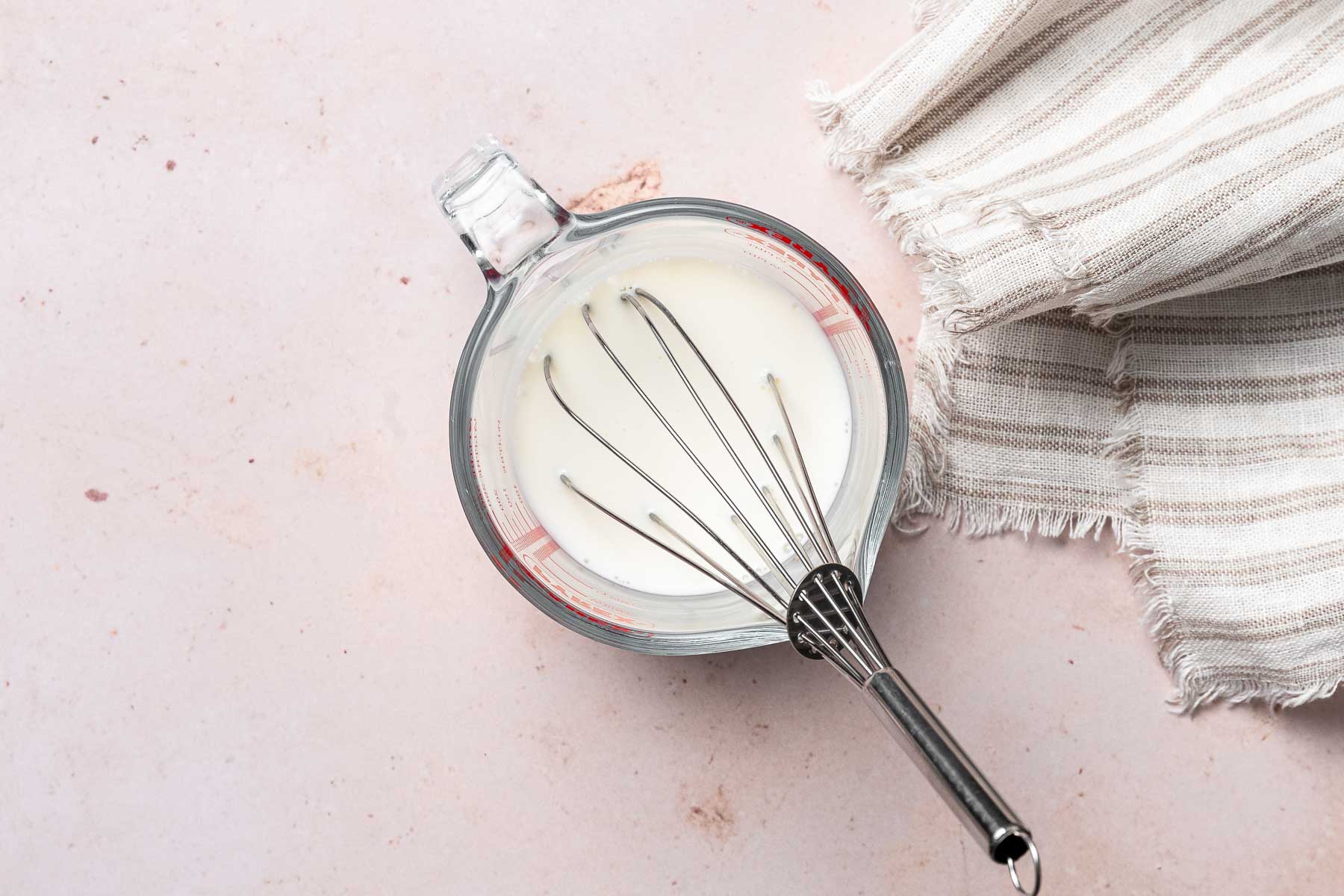 Milk in measuring cup with a whisk.