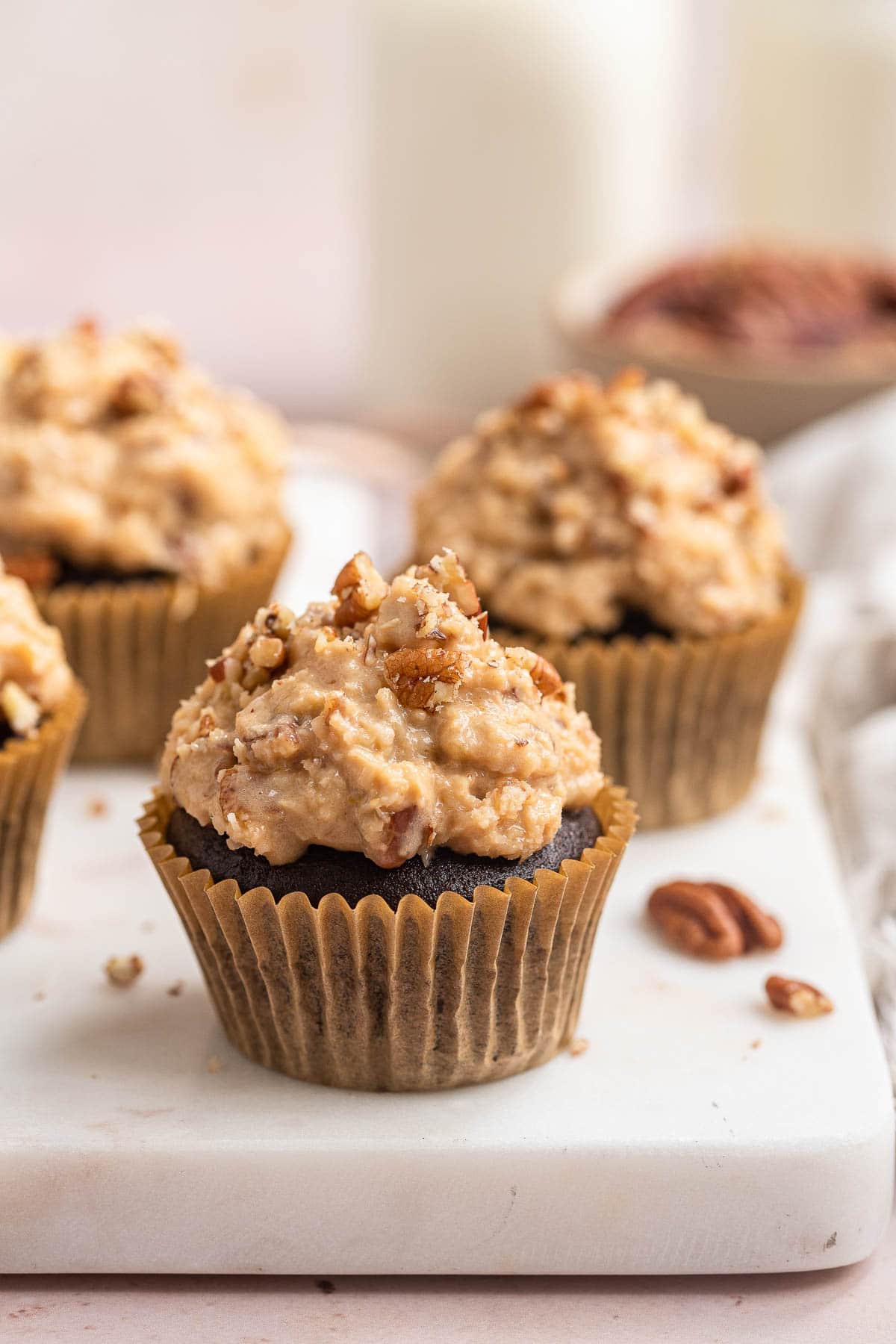 Chocolate cupcakes with creamy coconut frosting on top on white board.