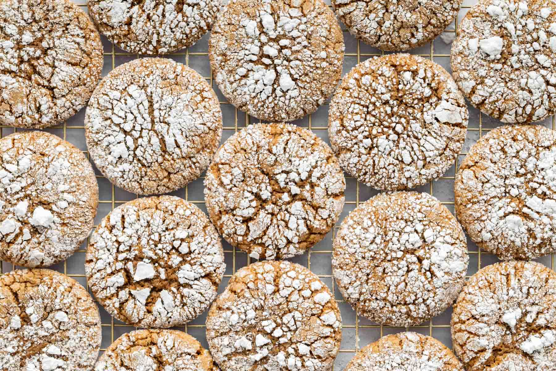 Horizontal image of crackled ginger crinkle cookies on a wire rack.