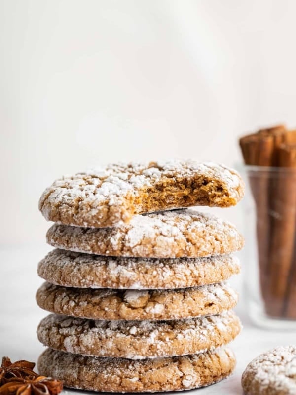 Stack of gingerbread crinkle cookies with bite missing from top cookie.