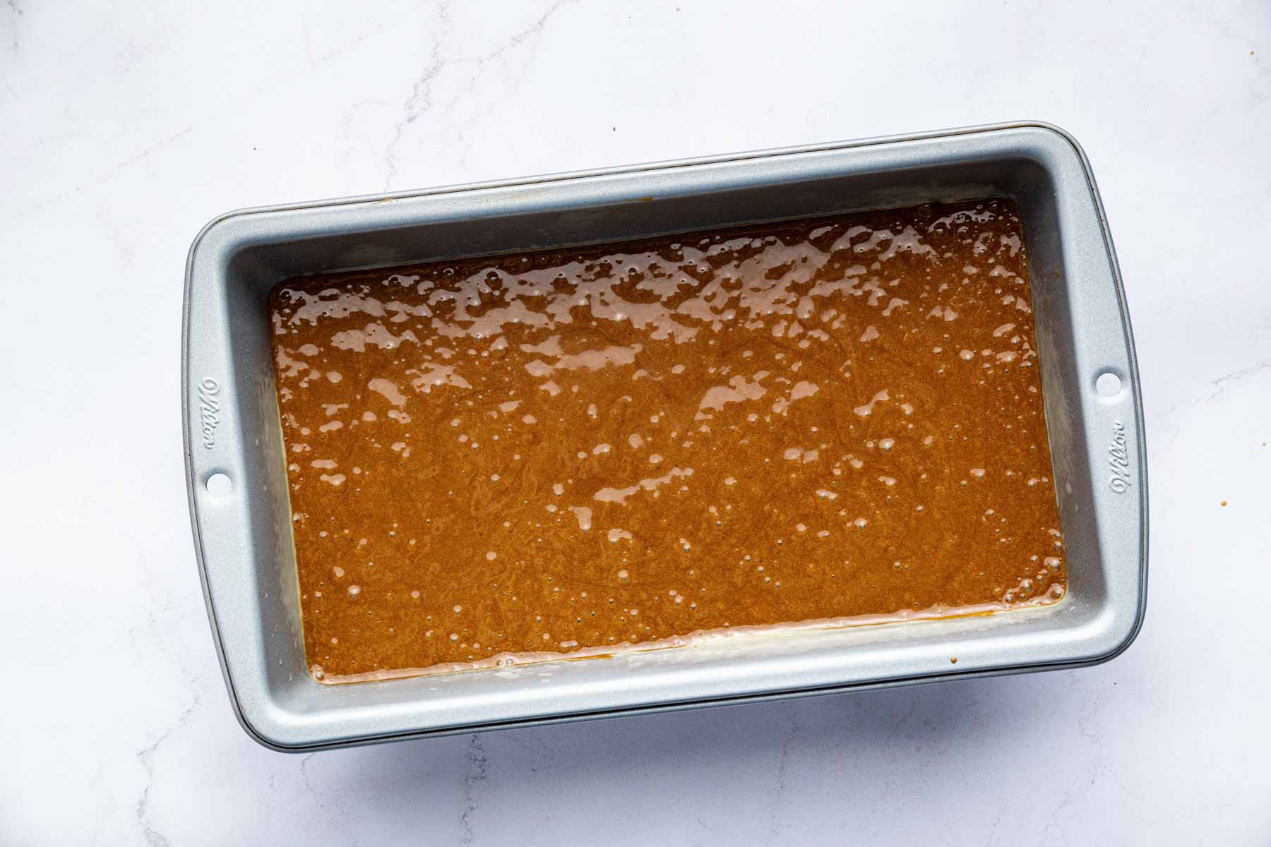 Raw gingerbread cake batter in a loaf pan.