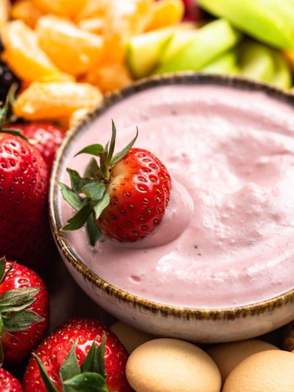 Pink fruit dip in a bowl with fresh strawberry on top.