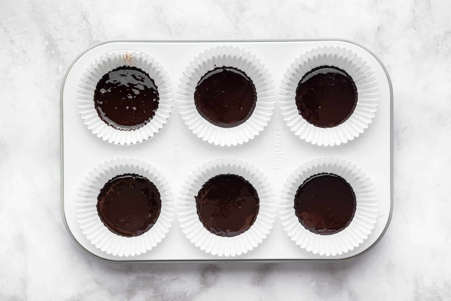 Six chocolate desserts in a muffin pan.