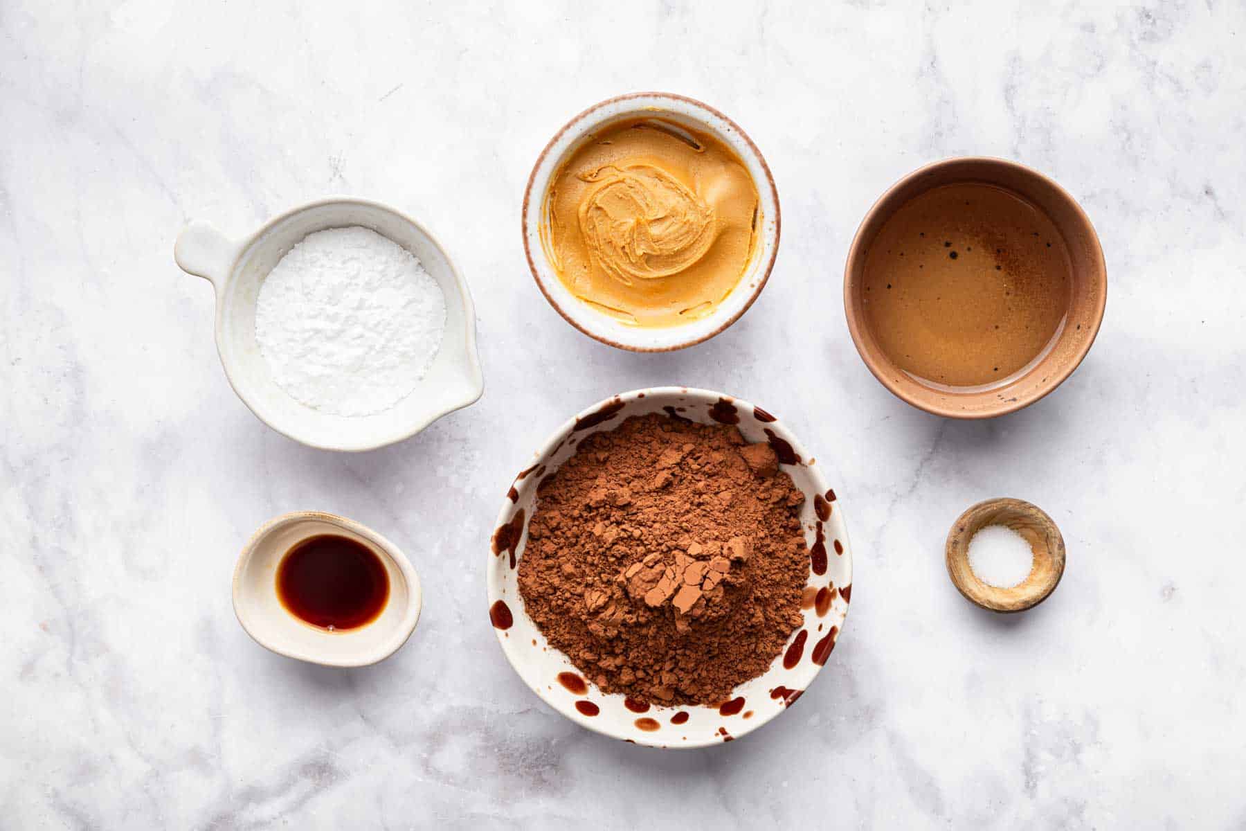 Small bowls with cocoa powder, nut butter, powdered sugar and salt.