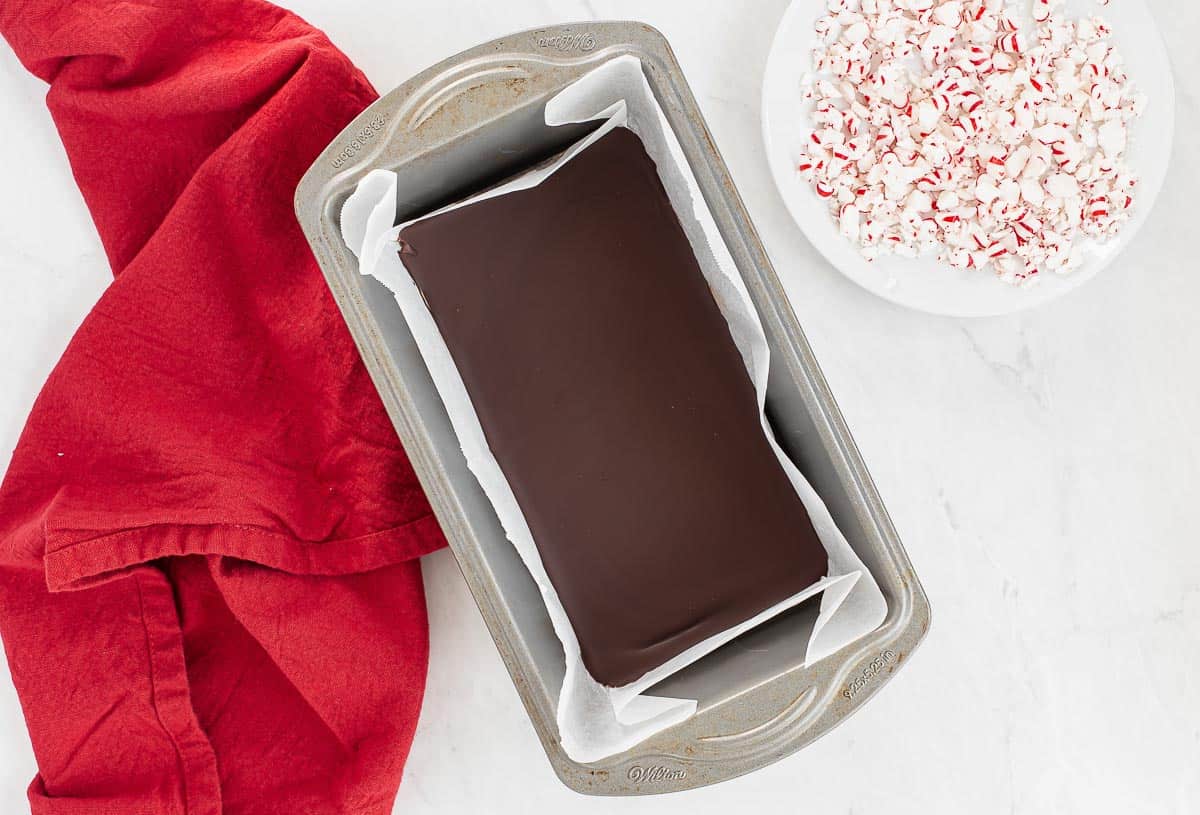 set chocolate in a loaf pan with crushed peppermints on the side