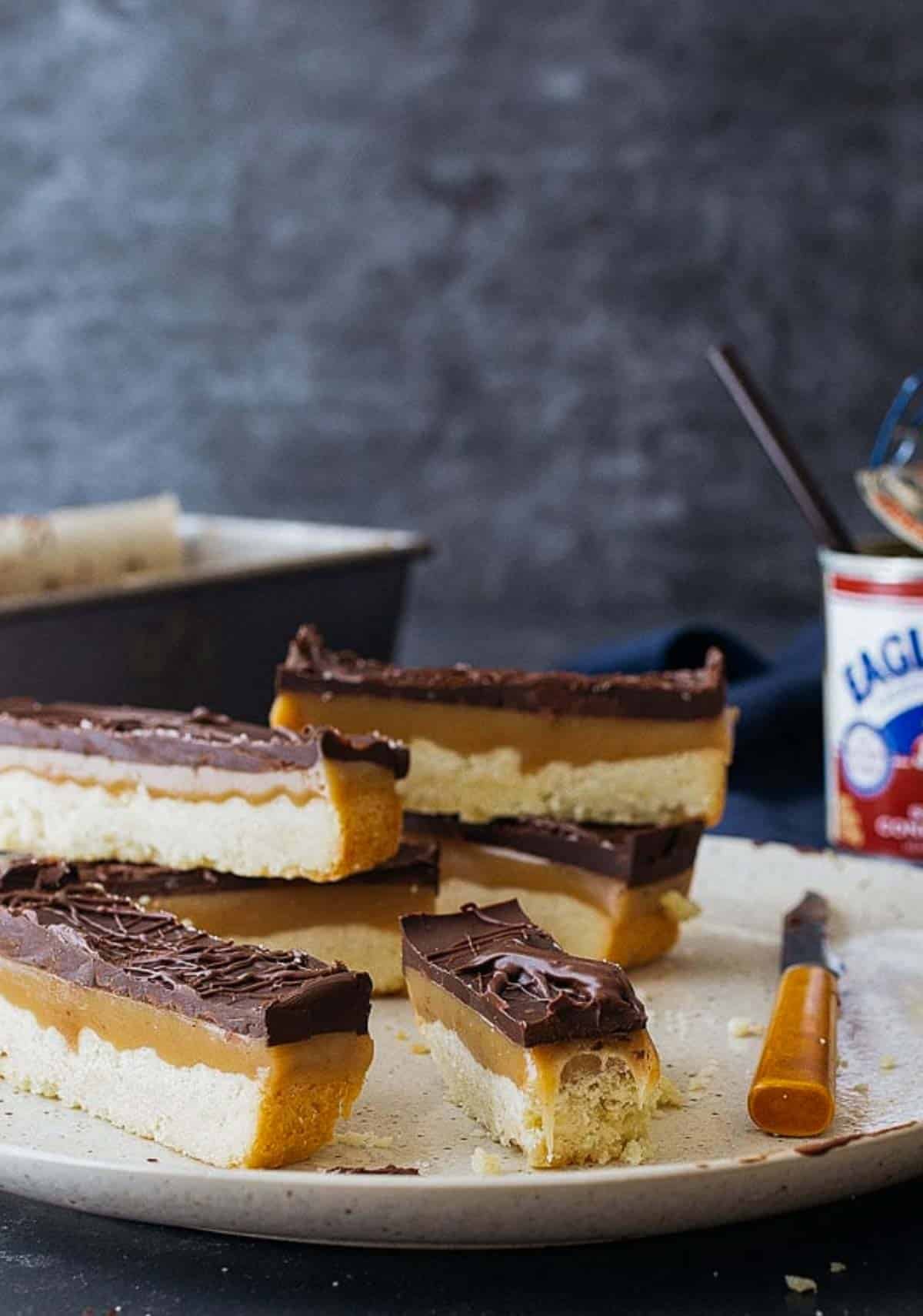 Homemade Twix bars on a plate with a bite missing to show chewy caramel.
