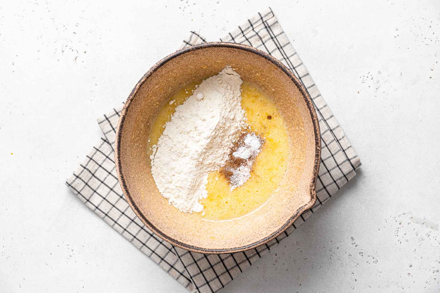 Adding flour and cinnamon to raw yellow batter.