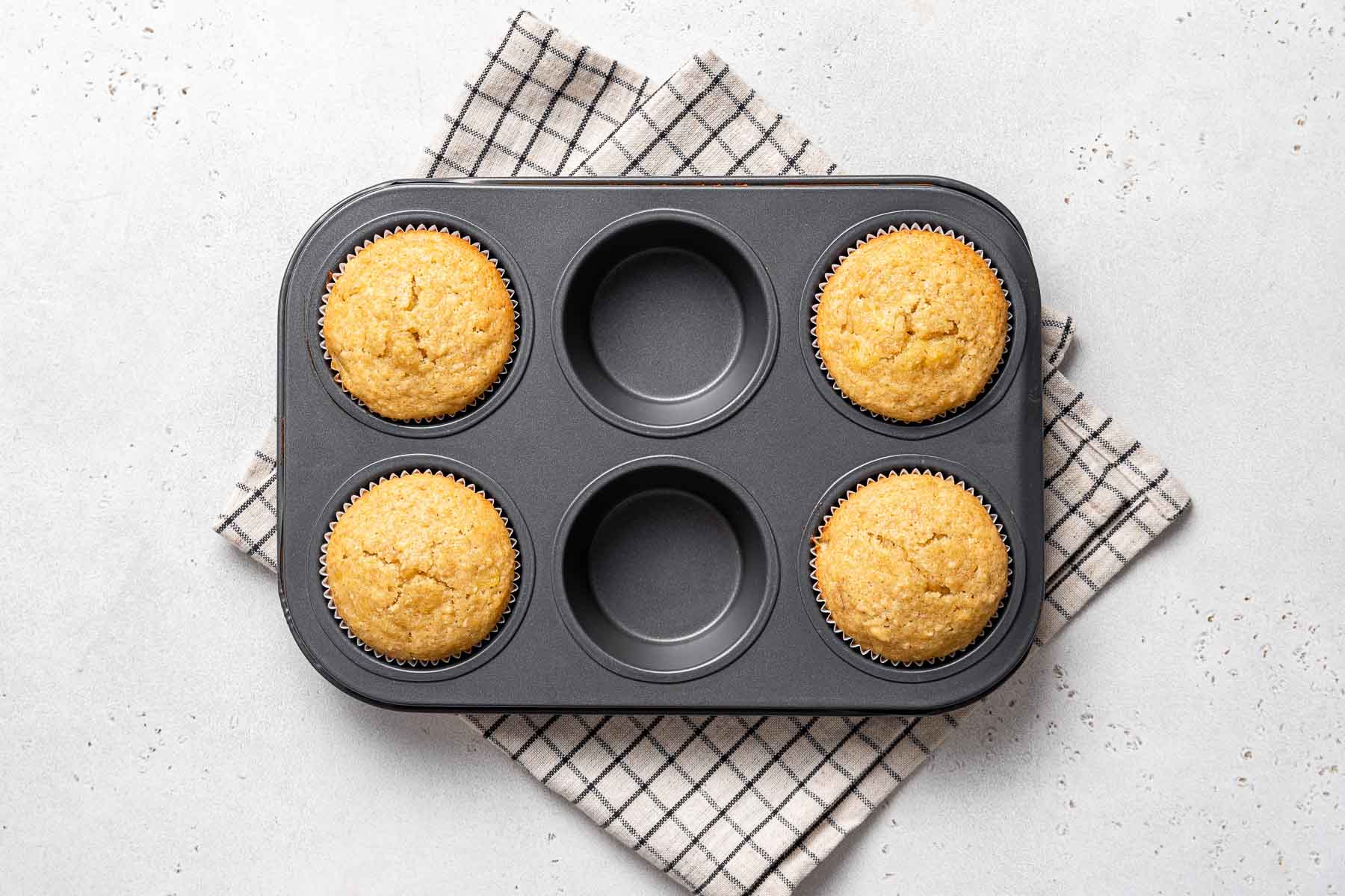 Four baked cupcakes in a muffin pan.