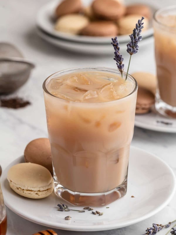 Iced London Fog tea latte on plate with lavender buds and macaron cookies.