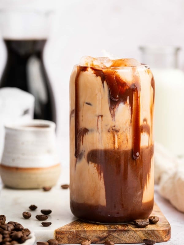 Vertical image of chocolate smeared iced mocha recipe with coffee beans.