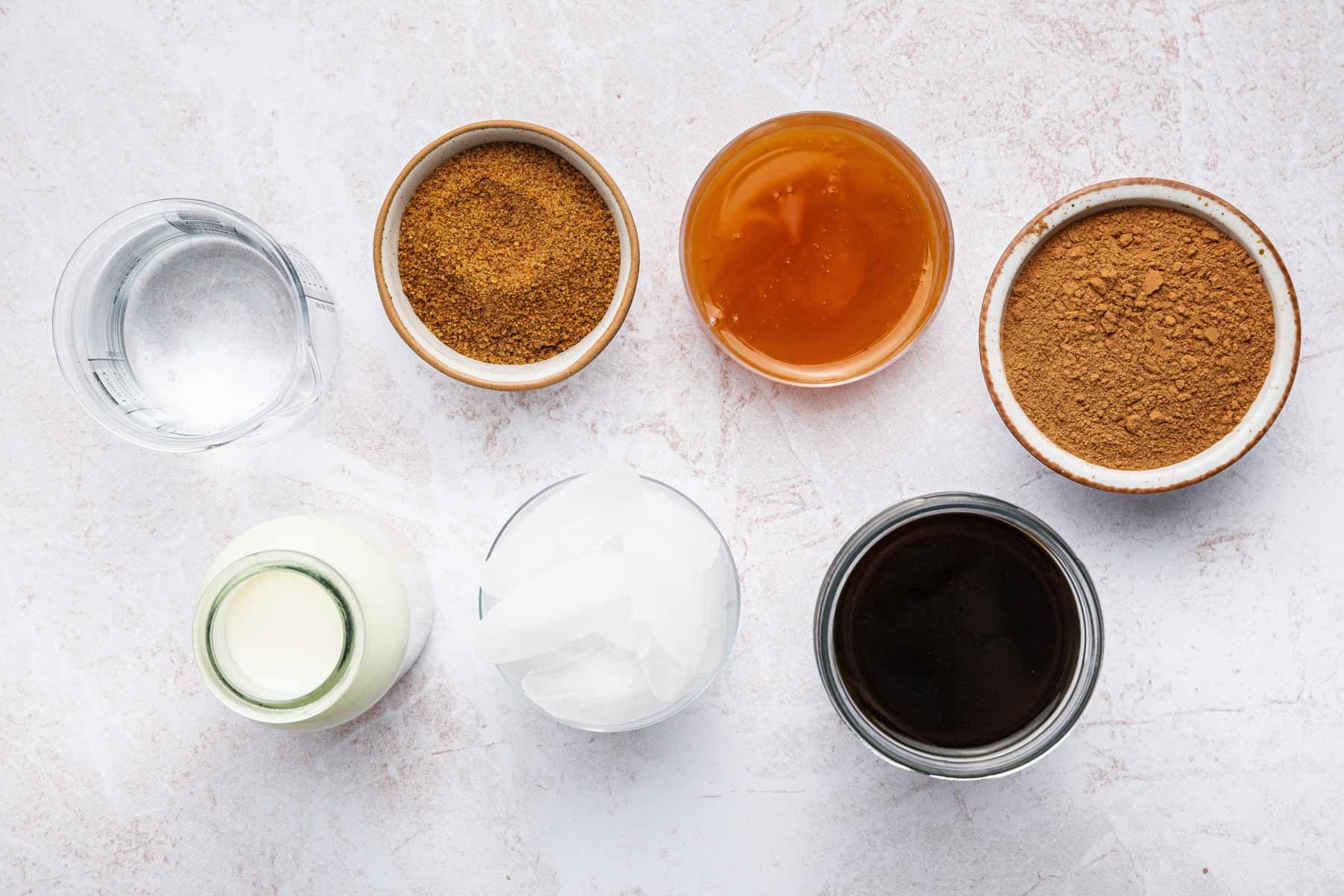 Small bowls of sugar, milk and ice on a kitchen counter.