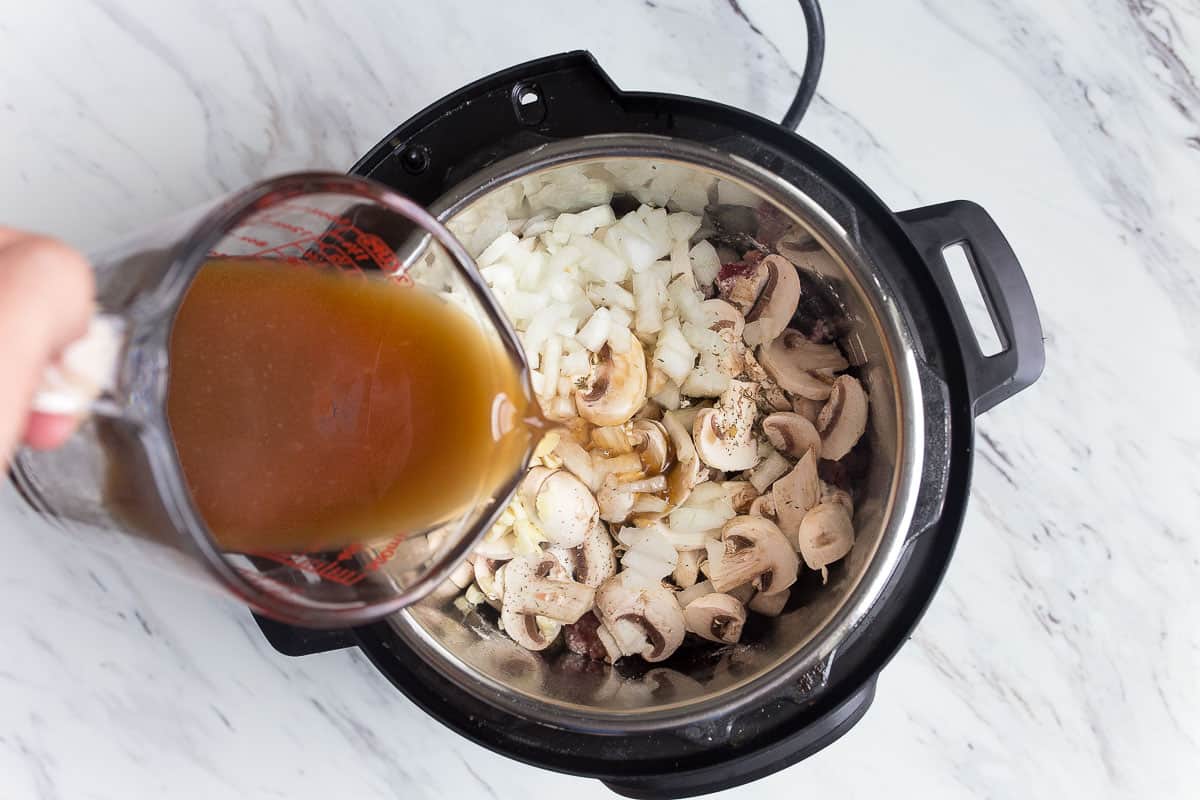 beef broth pouring into pressure cooker