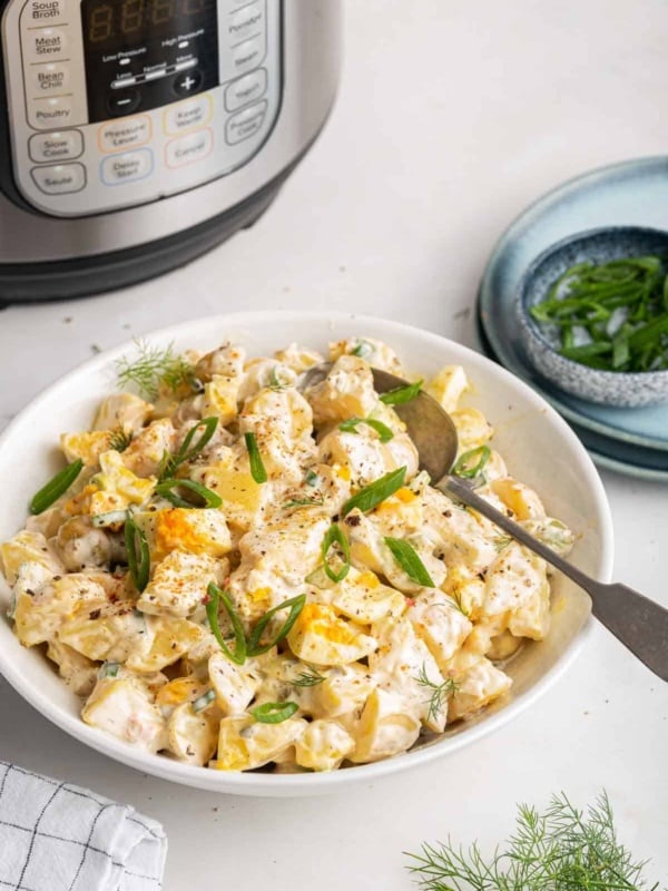 Bowl of potato salad with instant pot pressure cooker in the background.