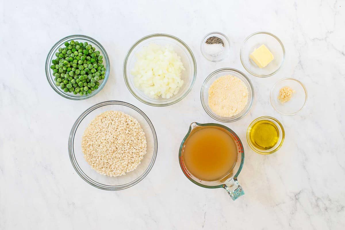 Ingredients for risotto: peas, rice, broth, spices, and vegetables.