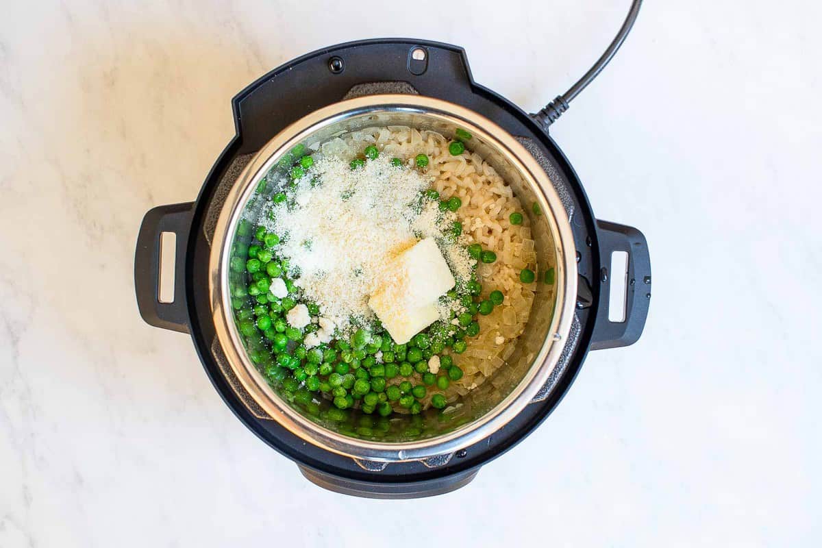 Instant pot with rice and peas and Parmesan cheese on top.