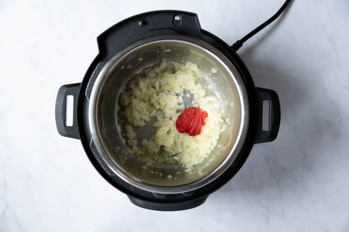 Tomato paste with onions cooking in instant pot.