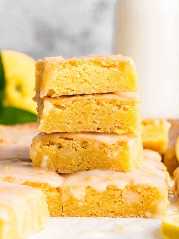Three stacked lemon brownies on a grey surface.