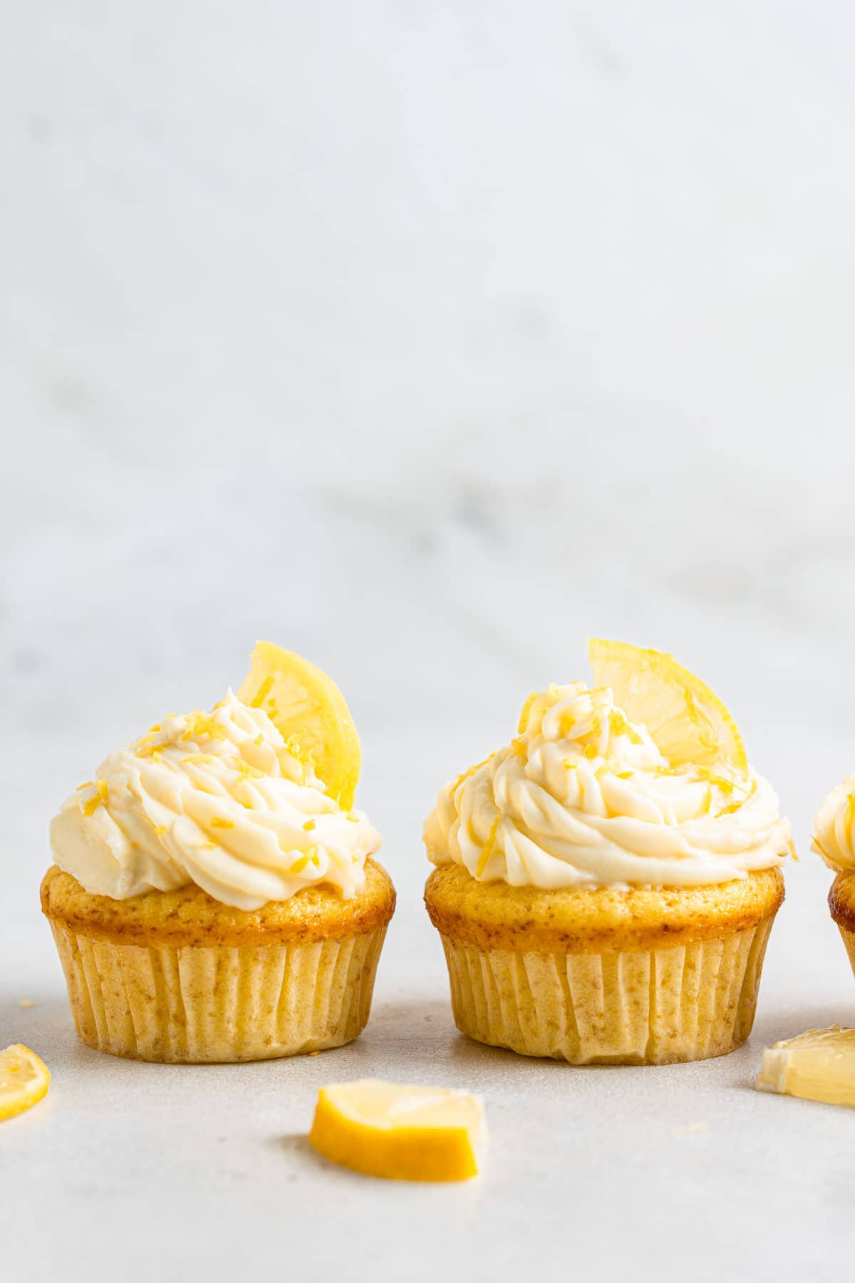 Two lemon cupcakes with fresh lemon slices.