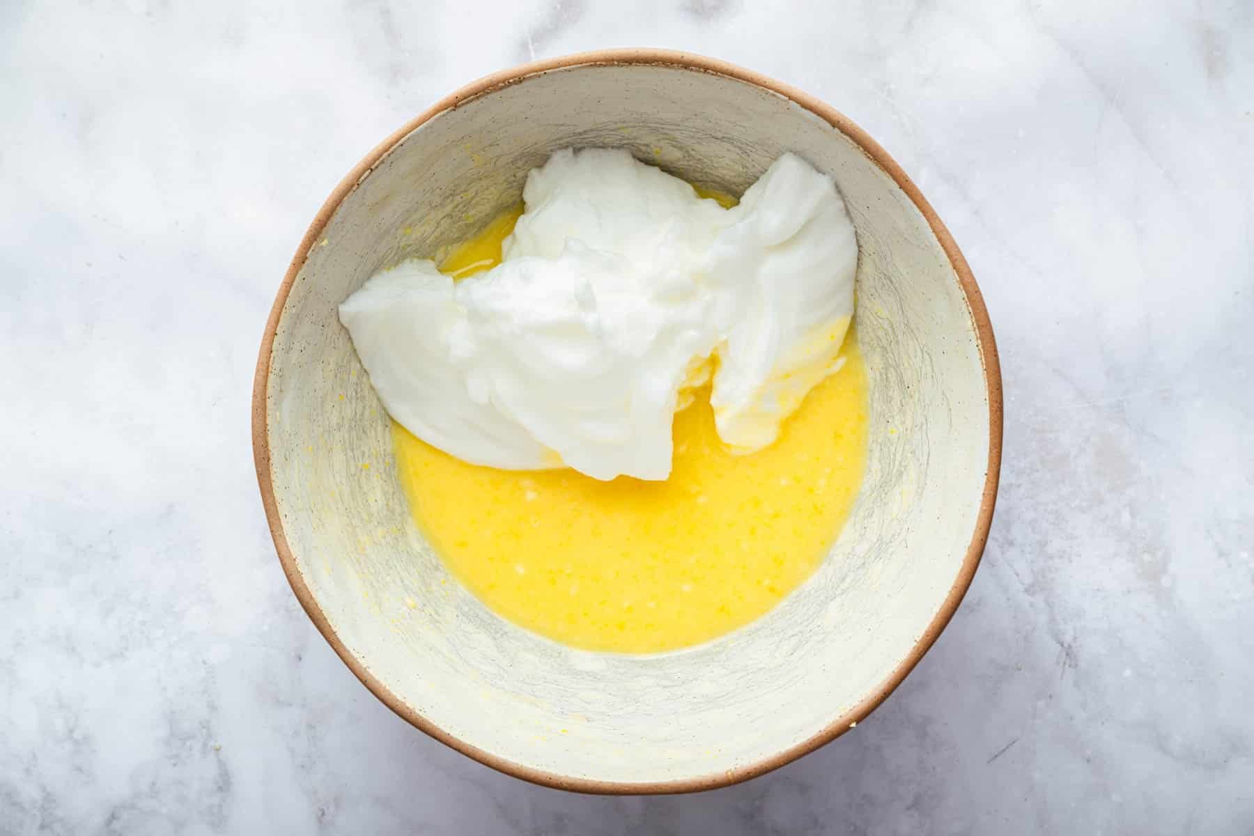 Yellow batter with fluffy whipped egg white on top, about to be stirred in.