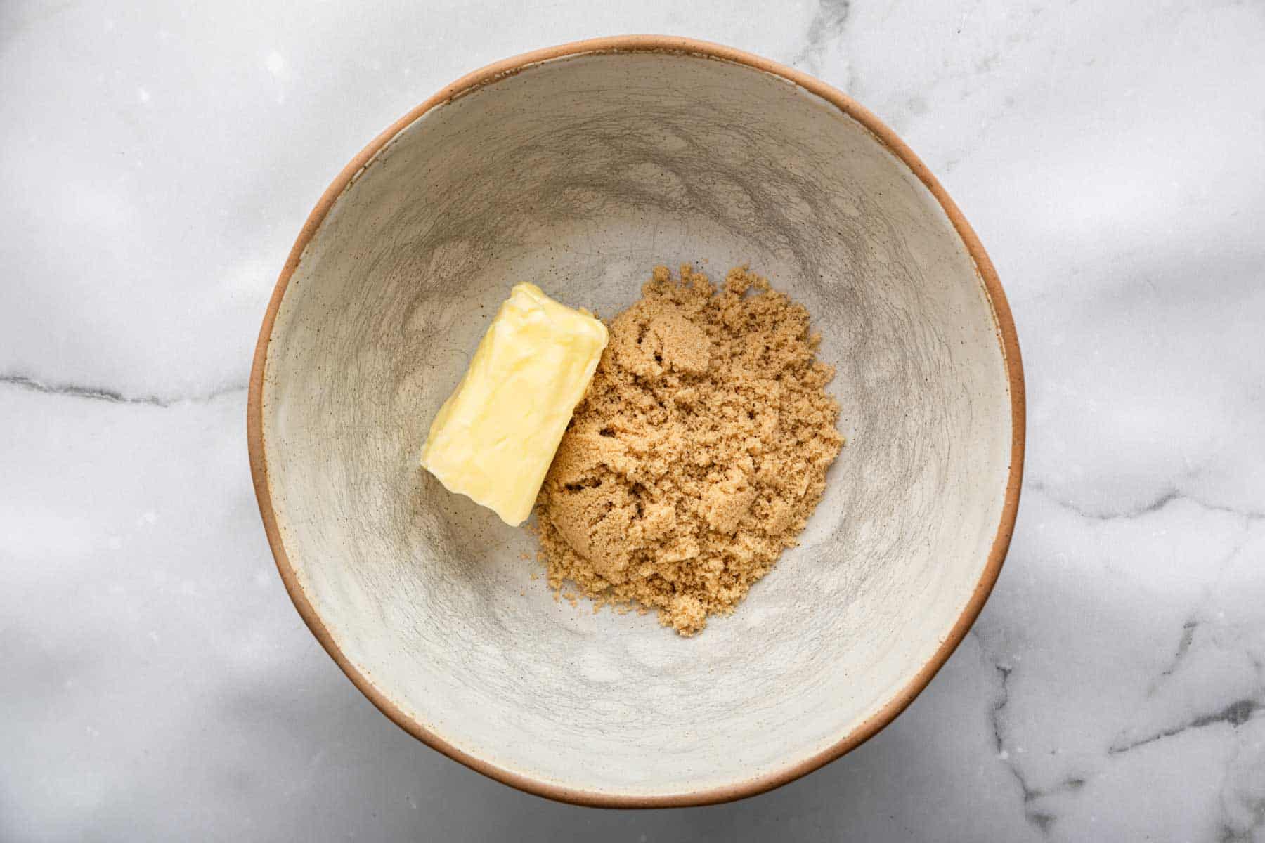 Grey pottery bowl with brown sugar and softened butter inside.