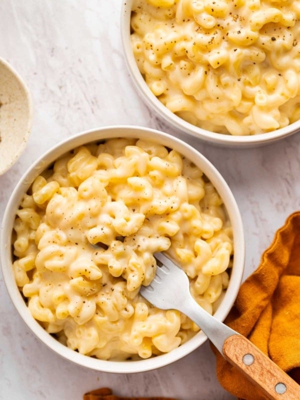 Two bowls of Mac and cheese with a fork in one bowl.