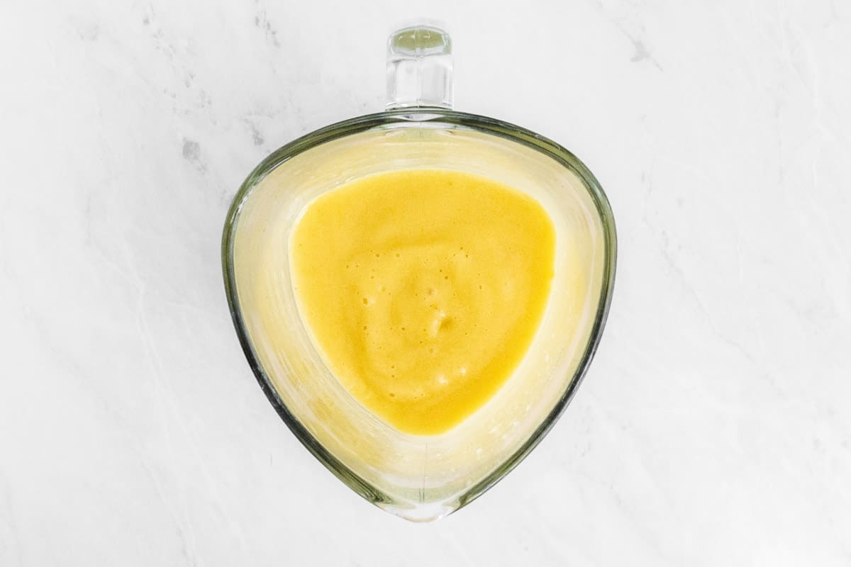 Orange smoothie in clear blender.